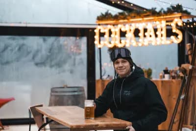 Gast met een biertje aan een houten tafel in de Hideout