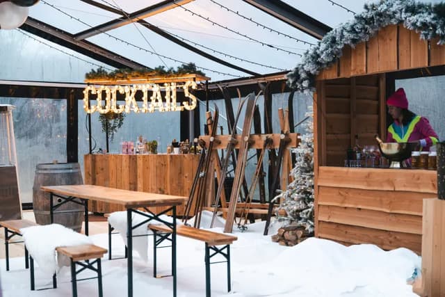 Houten tafels, sneeuw en ski's in de kastent van de Après Ski Hideout
