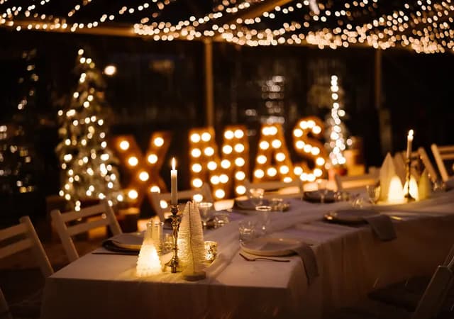Gedekte kersttafel met lichtgevende XMAS-letters in de kas van de Christmas Hideout